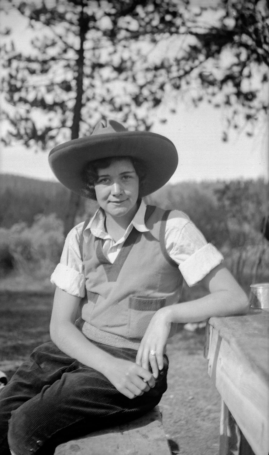black and white photo of a young woman wearing a sweater vest and large cowboy hat in a wilderness setting. From the Lora Webb Nichols collection; titled 'Wilbur Scafe's Pack Trip: Ruth, 1932'