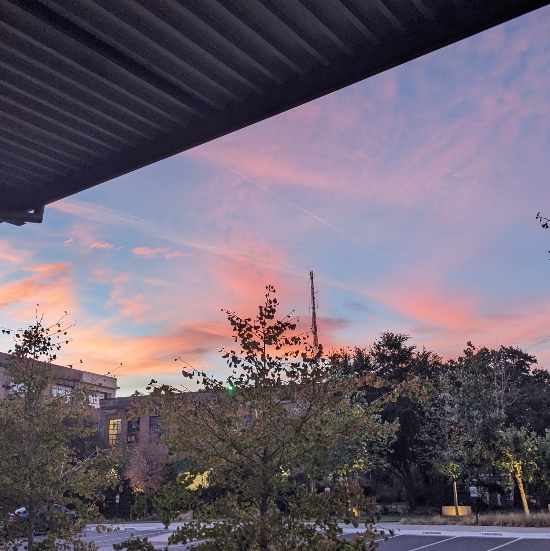 Sunrise with orangey-pink wispy clouds taken in a complex of early 1900s industrial buildings in Dallas, Texas USA on October 21, 2023