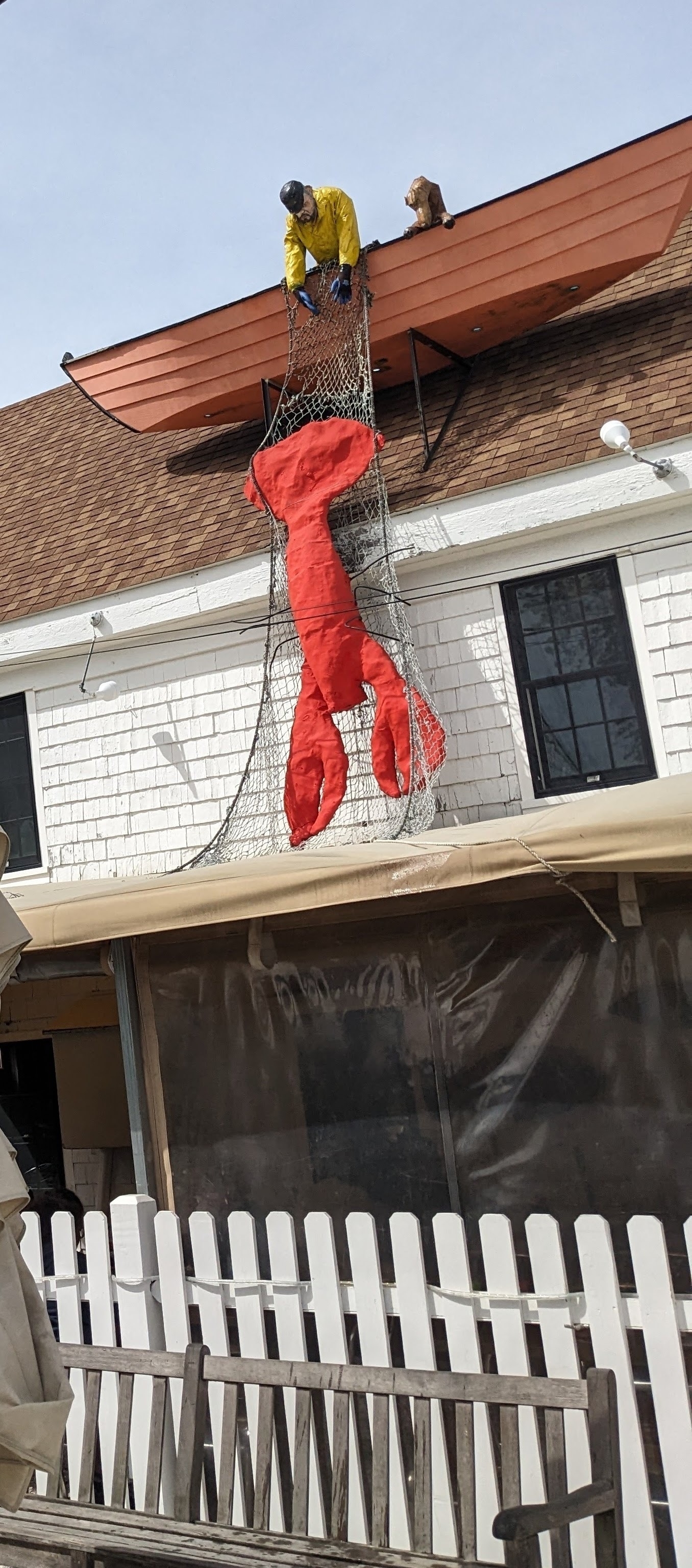 Seafood restaurant on Cape Cod with a giant lobster, boat, and lobsterman sculpture on the rood of the building.