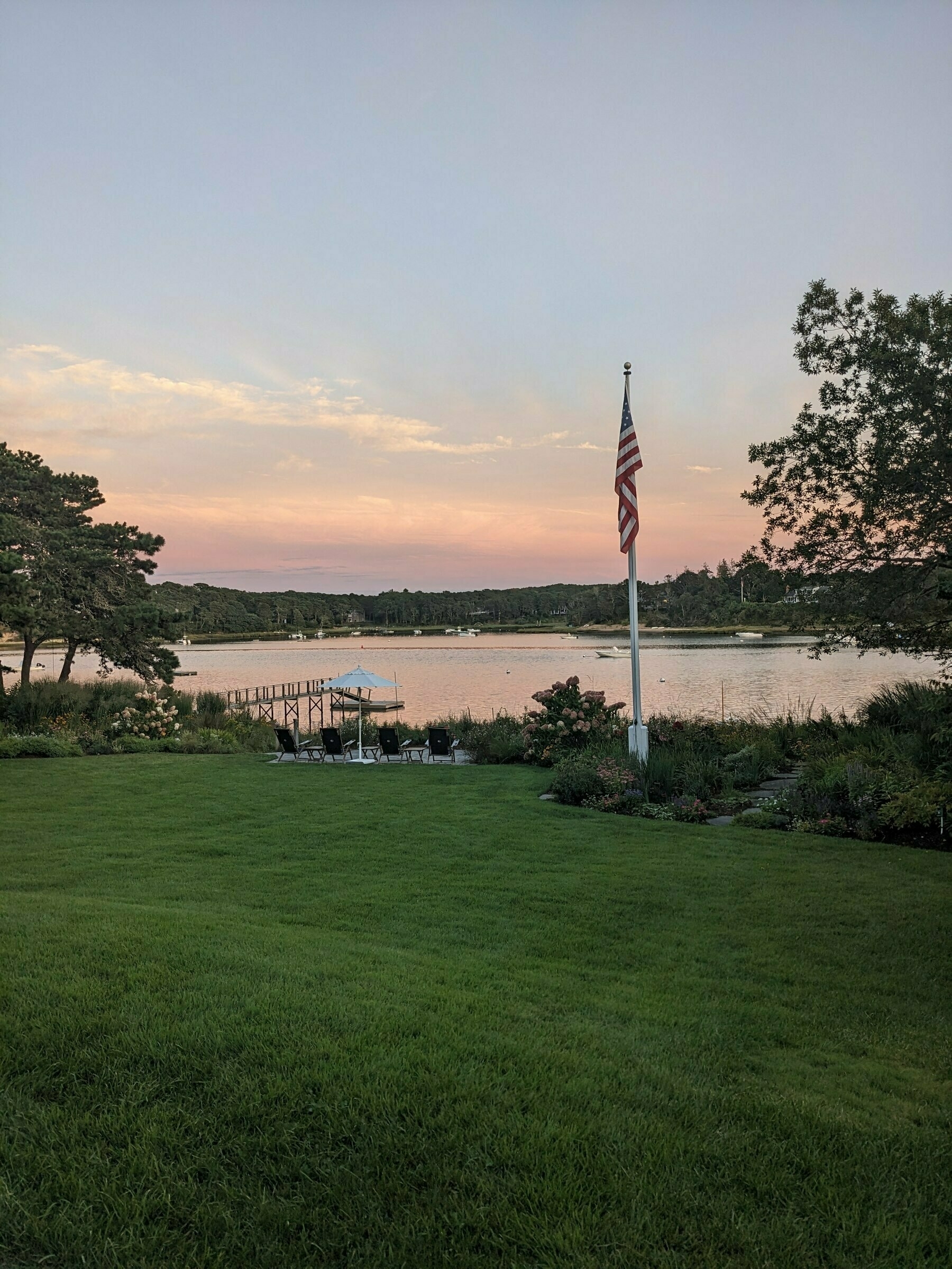 Cape Cod sunset  showing subtle light blue and peach clouds with American flag on a flag pole
