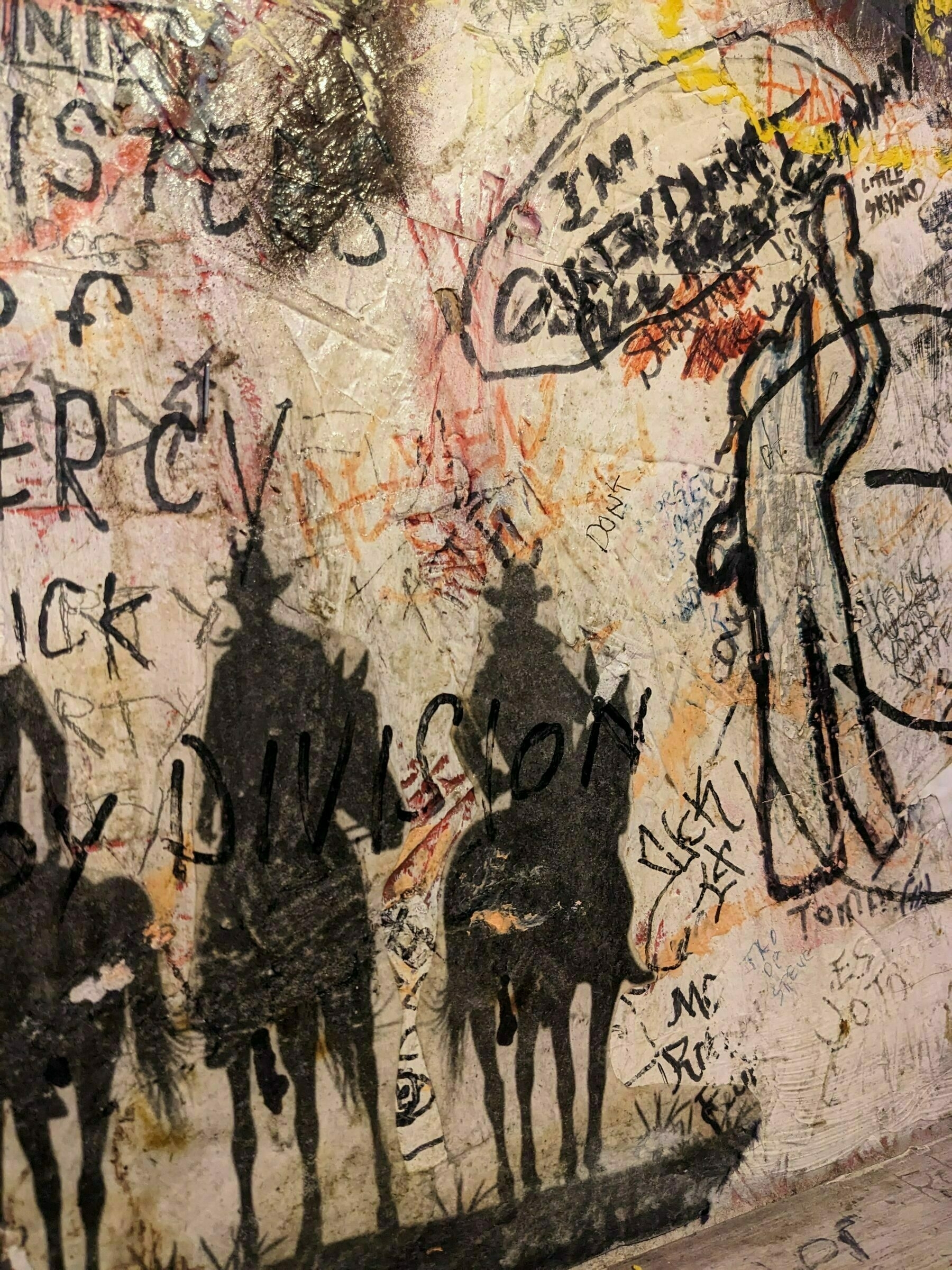 stenciled cowboys on horseback in silouhette painted on a restroom wall